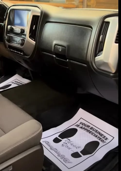 Vehicle dashboard and steering wheel with footprint mat showing business message on passenger seat