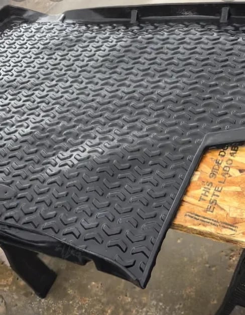 Black rubber truck bed liner mat with diamond plate pattern texture inside vehicle cargo area