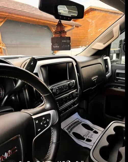 Interior of pickup truck showing dashboard, steering wheel, center console, and a wood garage in the background