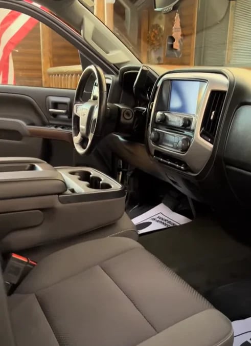 Interior view of a truck dashboard with steering wheel, touchscreen display, and gray leather seats in a showroom